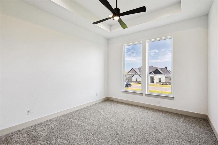 Empty room featuring ceiling fan, carpet floors, and a tray ceiling