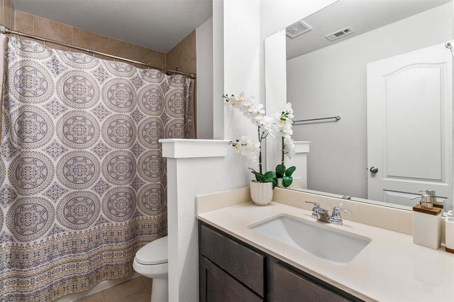 Bathroom with toilet, a shower with curtain, vanity, and tile patterned flooring