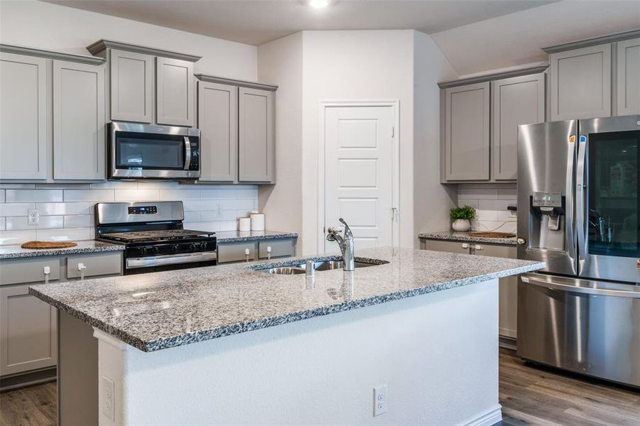 Kitchen featuring decorative backsplash, a center island with sink, dark hardwood / wood-style flooring, sink, and stainless steel appliances