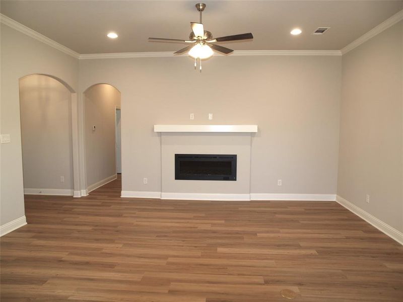 Unfurnished living room with ceiling fan, dark hardwood / wood-style floors, and crown molding