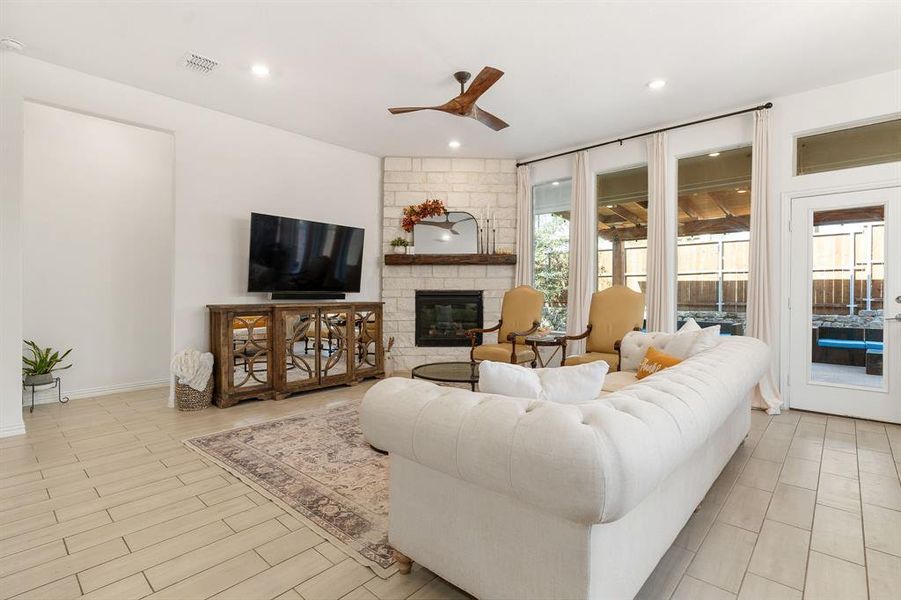 Living room with light hardwood / wood-style flooring, ceiling fan, a fireplace, and a wealth of natural light