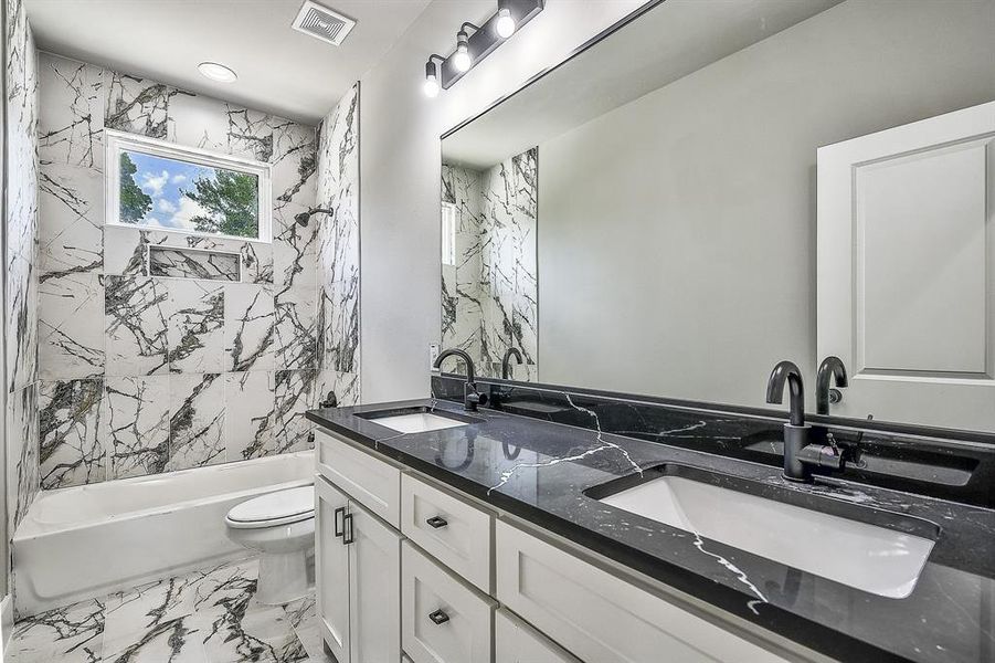 Full bathroom with tiled shower / bath, dual vanity, toilet, and tile floors