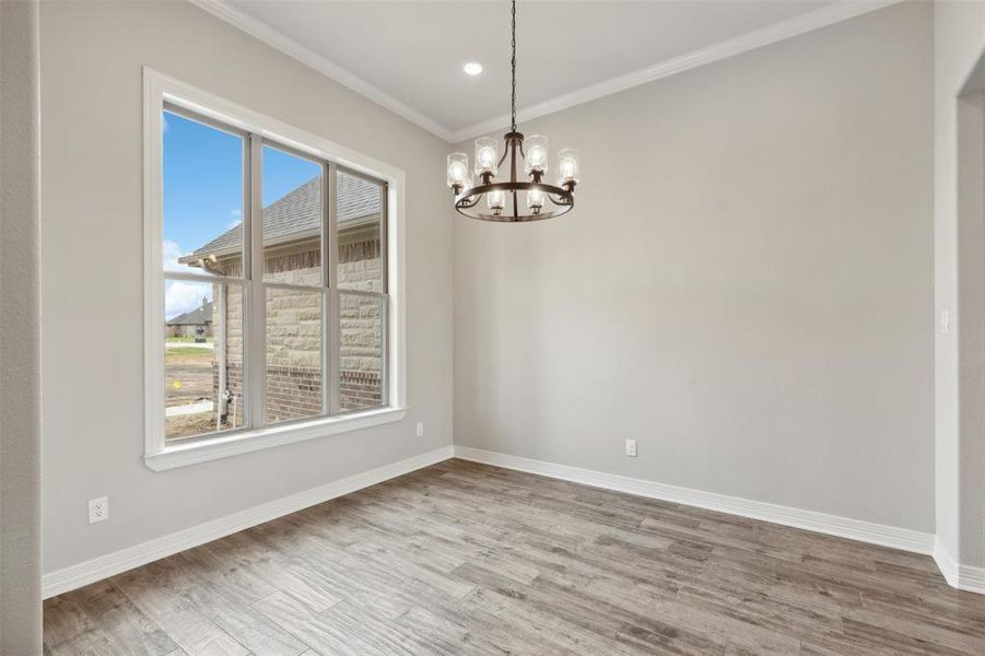 Unfurnished room with wood-type flooring, a chandelier, and plenty of natural light