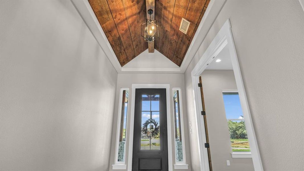 Foyer with vaulted wood ceiling and large metal door