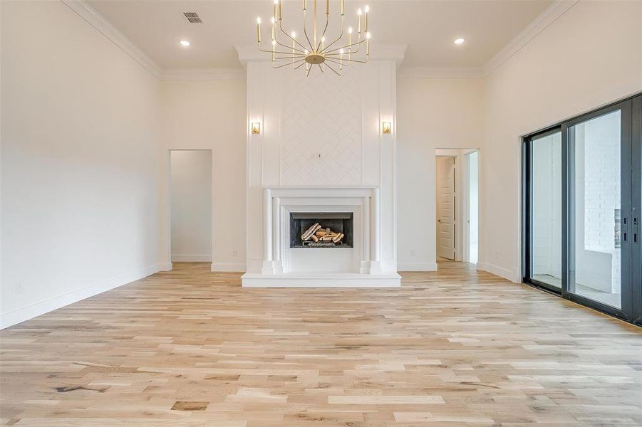 Unfurnished living room with light wood-type flooring, crown molding, and plenty of natural light