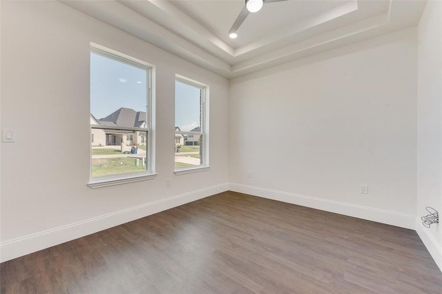 Spare room featuring dark wood-type flooring, a tray ceiling, and ceiling fan