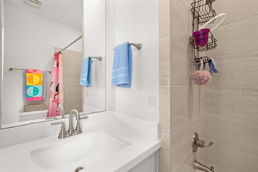 The bathroom in the fifth bedroom is equipped with a tiled shower/tub combo, a sink vanity, and a toilet, providing essential amenities in a clean and functional space.