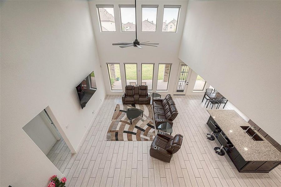 This is a spacious, high-ceilinged living room with large windows, modern furnishings, and an open floor plan that flows into the kitchen and dining area. It features sleek finishes and ample natural light.