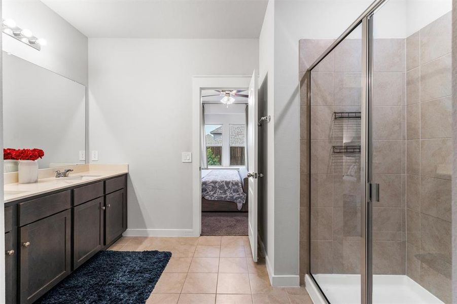 Bathroom with vanity, tile patterned flooring, ceiling fan, and a shower with door