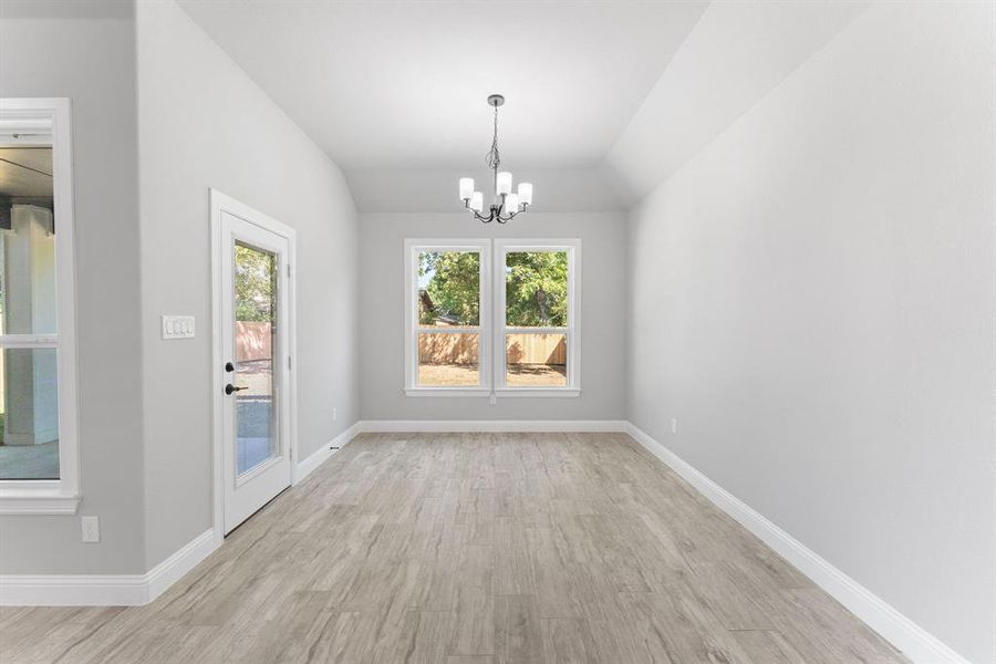 Unfurnished dining area with light wood-type flooring, a chandelier, and vaulted ceiling