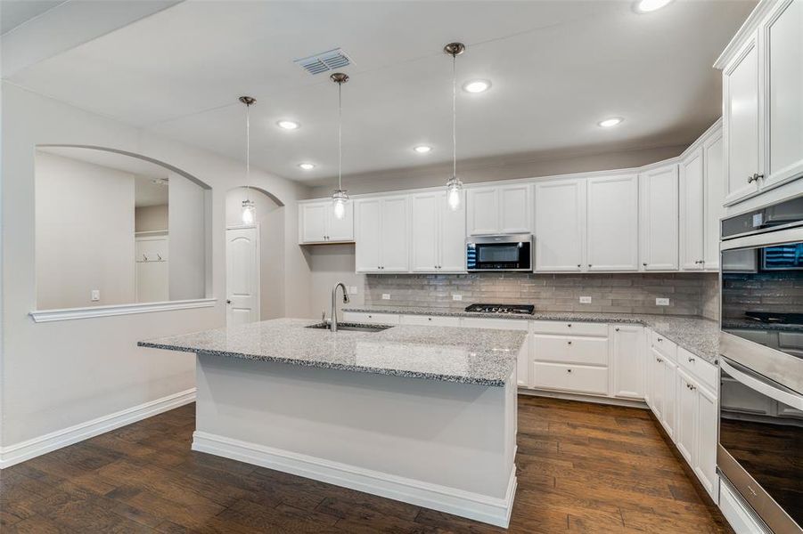 Kitchen featuring appliances with stainless steel finishes, white cabinetry, sink, and dark wood-type flooring