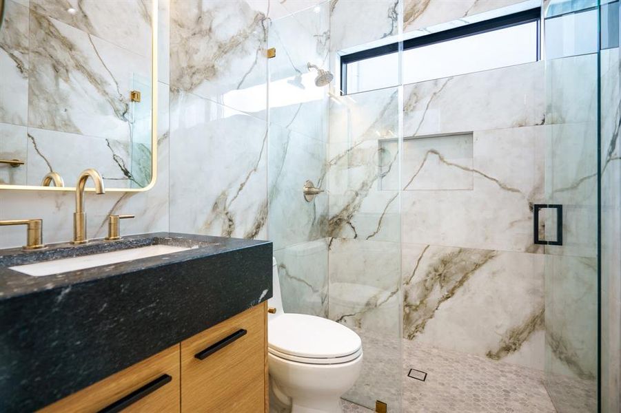 Bathroom featuring tile walls, a shower with shower door, vanity, and toilet