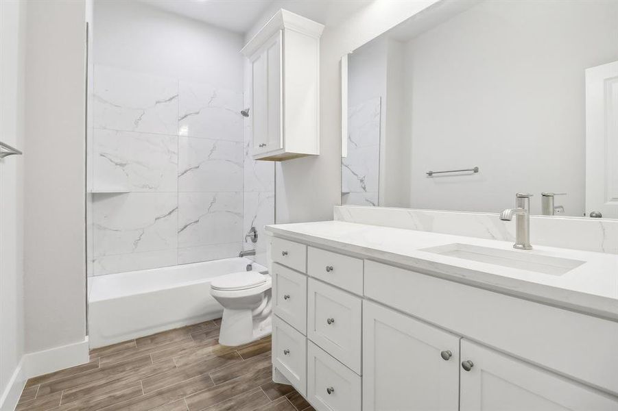 Full bathroom featuring tiled shower / bath, vanity, and toilet