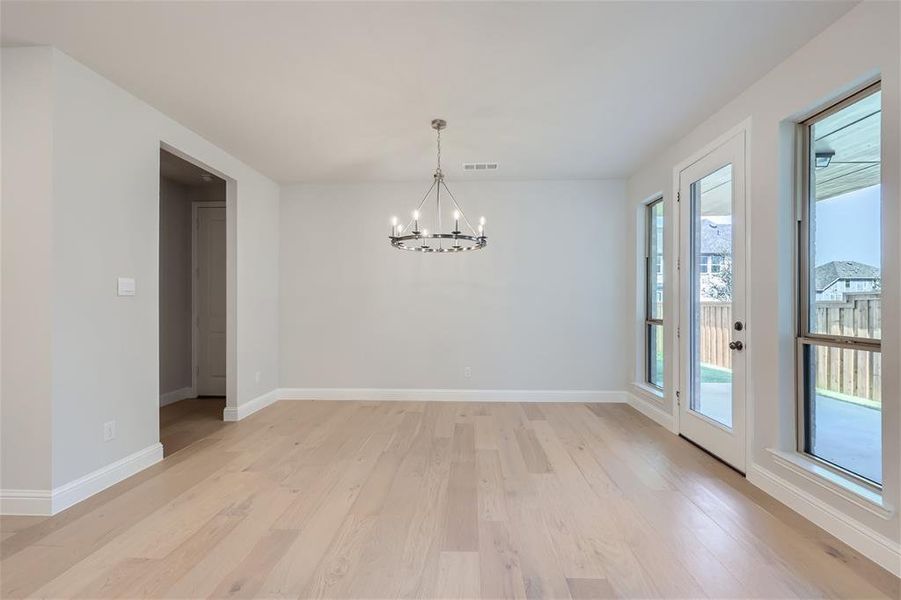 Unfurnished dining area with an inviting chandelier and light hardwood / wood-style floors