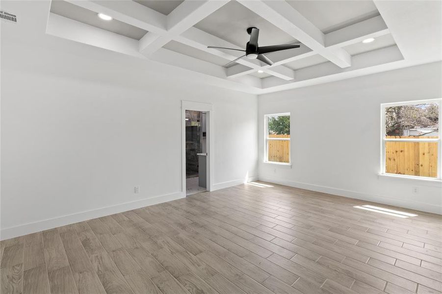 Spare room featuring light wood-type flooring, coffered ceiling, ceiling fan, and beamed ceiling