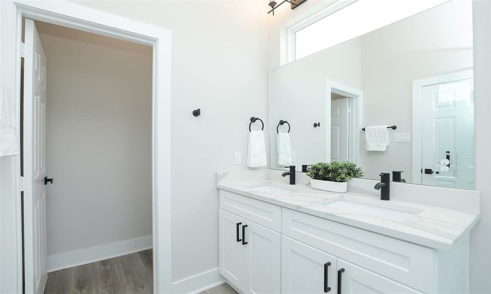 Primary bath has a double vanity, private water closet, gray veined quartz countertop, and modern fixtures.