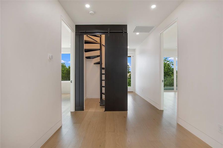 Corridor with a barn door and hardwood / wood-style floors