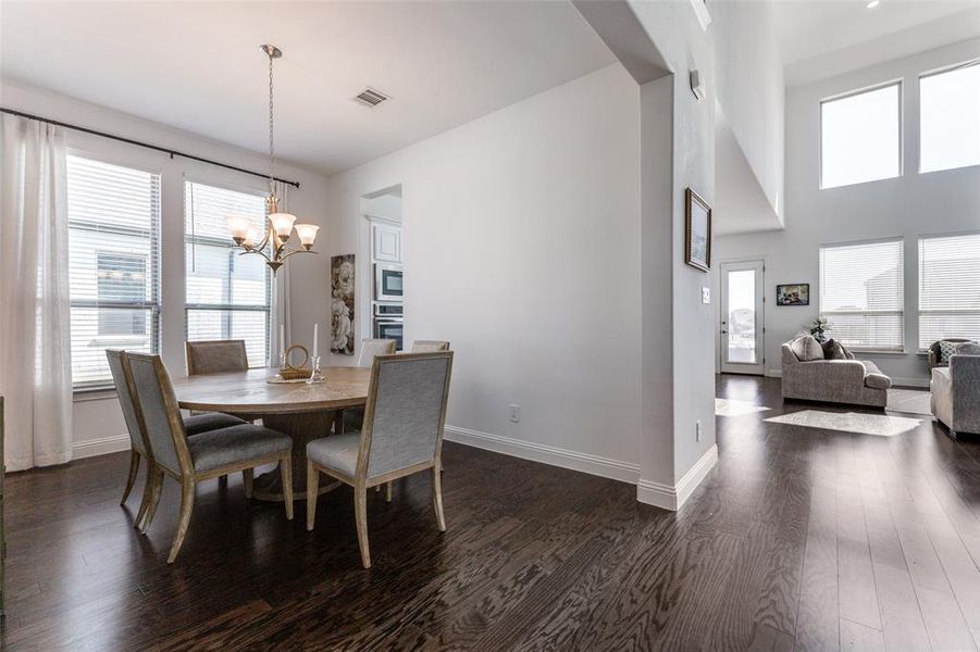 Dining space with an inviting chandelier, a high ceiling and wood flooring