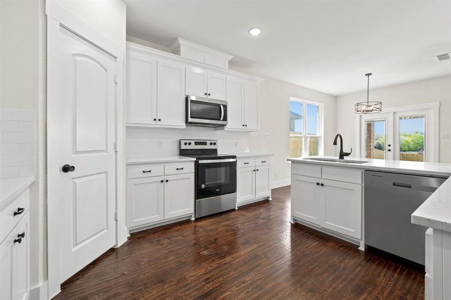 Kitchen with appliances with stainless steel finishes, dark wood-type flooring, sink, white cabinetry, and light stone counters