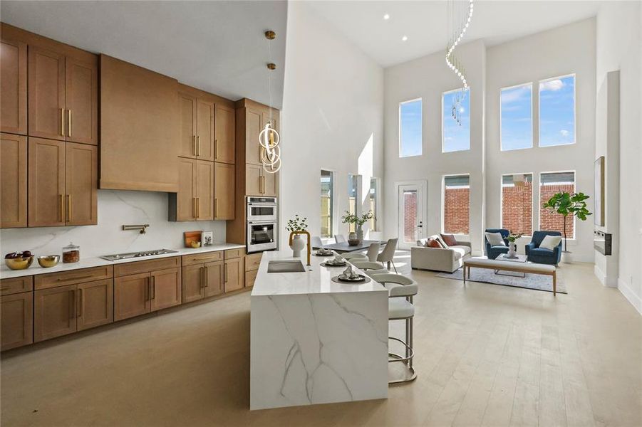 Kitchen with cooktop, a kitchen bar, a towering ceiling, double oven, and sink