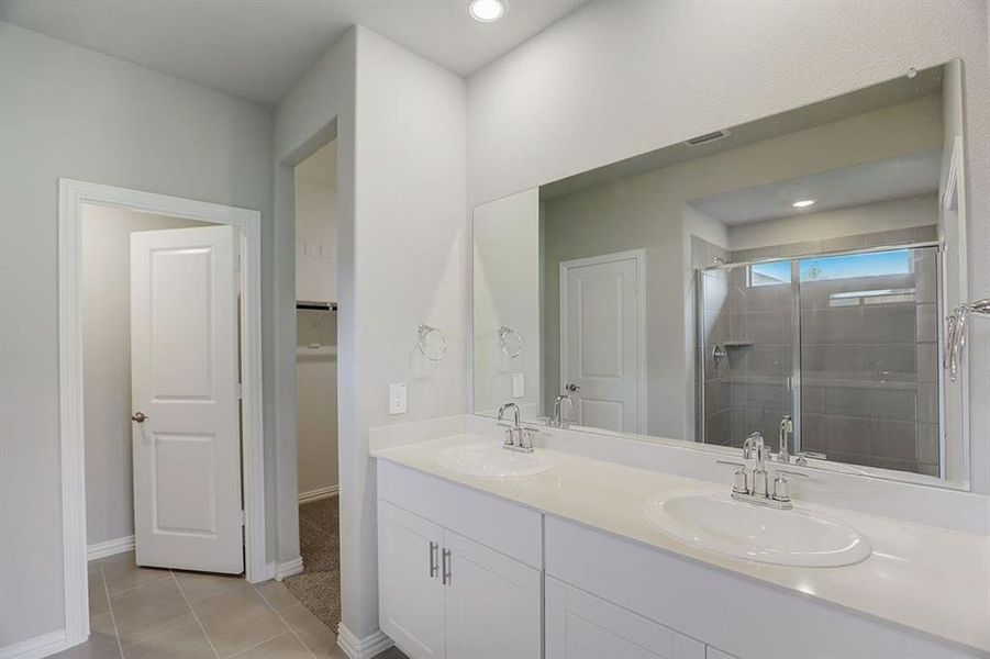 Bathroom featuring tile patterned flooring, a shower with door, and vanity