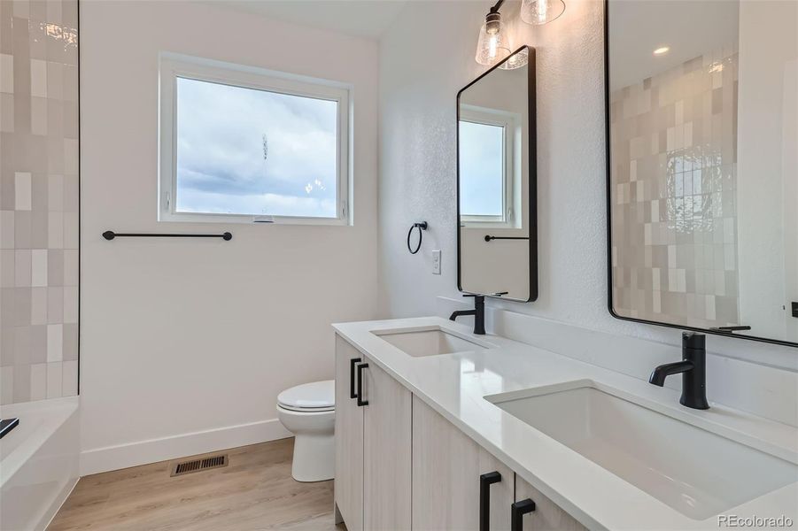 Large full bathroom on 3rd level with double vanity, quartz countertops, tub, and shower