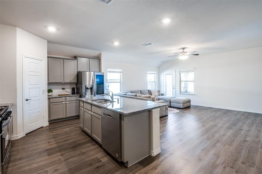 Kitchen with an island with sink, dark wood-type flooring, sink, gray cabinetry, and stainless steel appliances