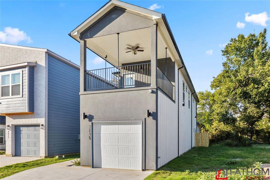 View of side of property featuring a balcony, a garage, and a lawn