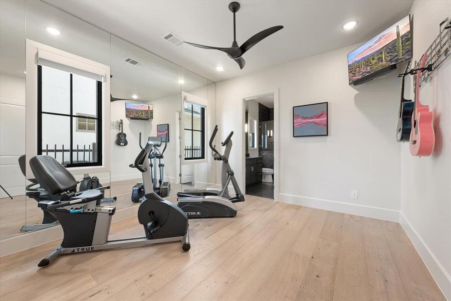 Workout room with light wood-type flooring and ceiling fan