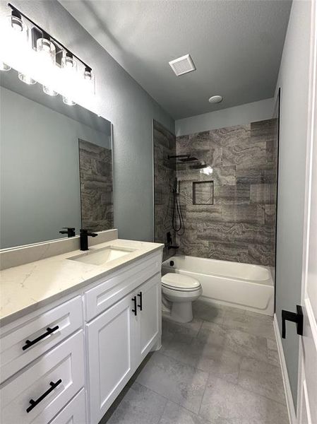 Full bathroom featuring vanity, toilet, a textured ceiling, and tiled shower / bath