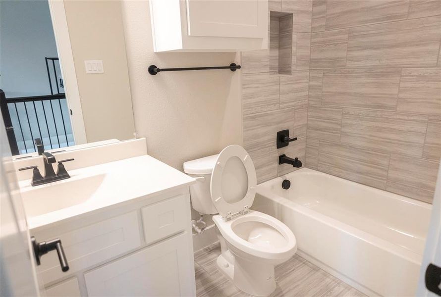 Full bathroom featuring tiled shower / bath combo, tile patterned floors, toilet, and vanity