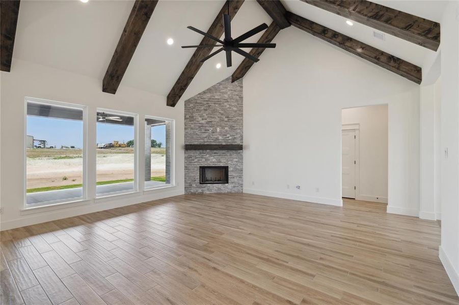 Unfurnished living room featuring ceiling fan, a fireplace, and high vaulted ceiling