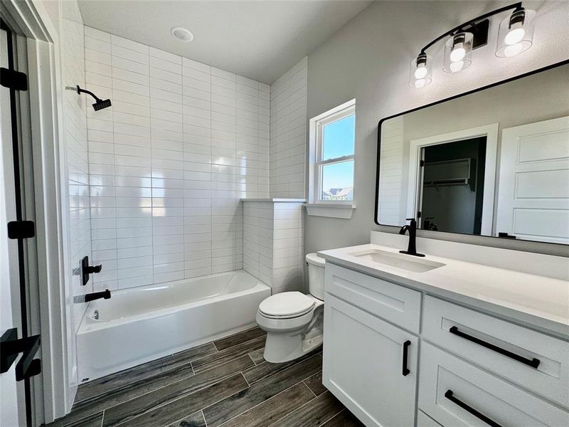 Full bathroom with tiled shower / bath combo, vanity, and toilet