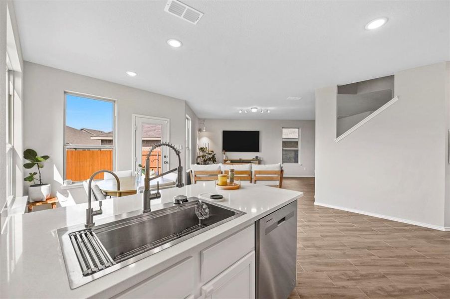 Kitchen with light hardwood / wood-style floors, sink, white cabinetry, and dishwasher