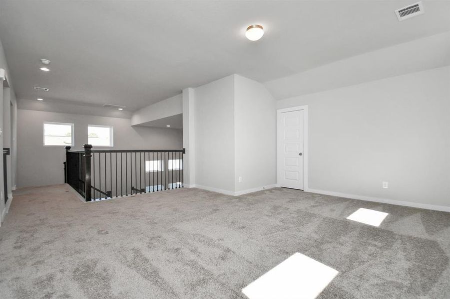 Come upstairs and relish a day of relaxation in this loft area! Ideal as an additional living space or game room, it boasts plush carpeting, high ceilings, custom paint, and windows that flood the area with abundant natural light.