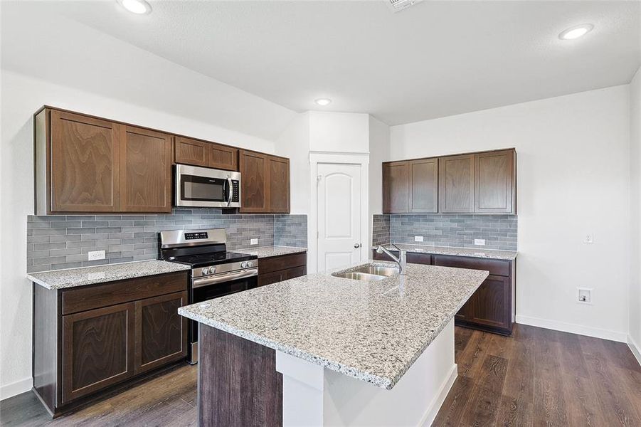 Kitchen with appliances with stainless steel finishes, dark hardwood / wood-style floors, decorative backsplash, and sink