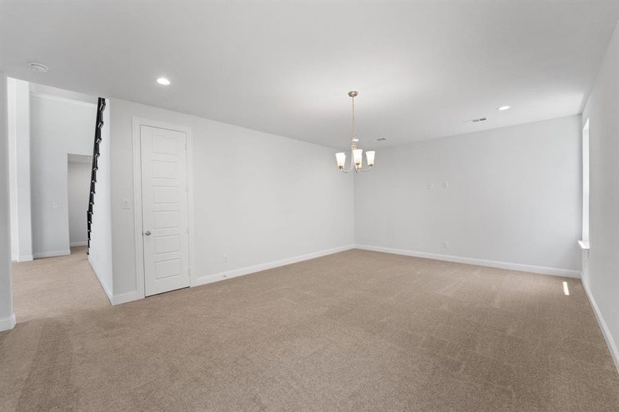 Spare room with a notable chandelier and light colored carpet