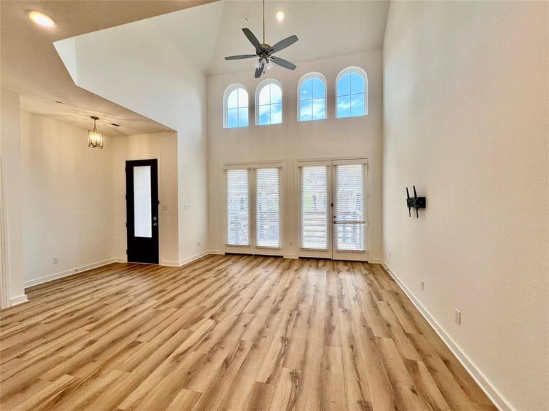 Empty room featuring light hardwood / wood-style floors, ceiling fan, and a towering ceiling