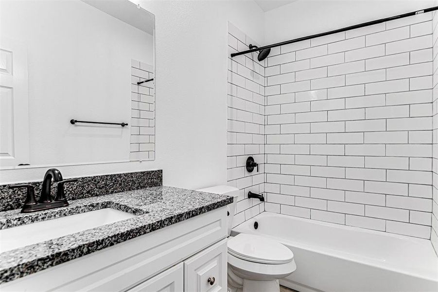 Full bathroom with vanity, tiled shower / bath, and toilet