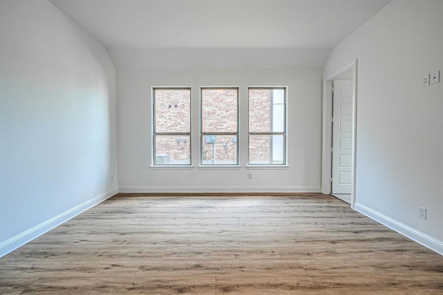 Empty room with light hardwood / wood-style flooring and vaulted ceiling