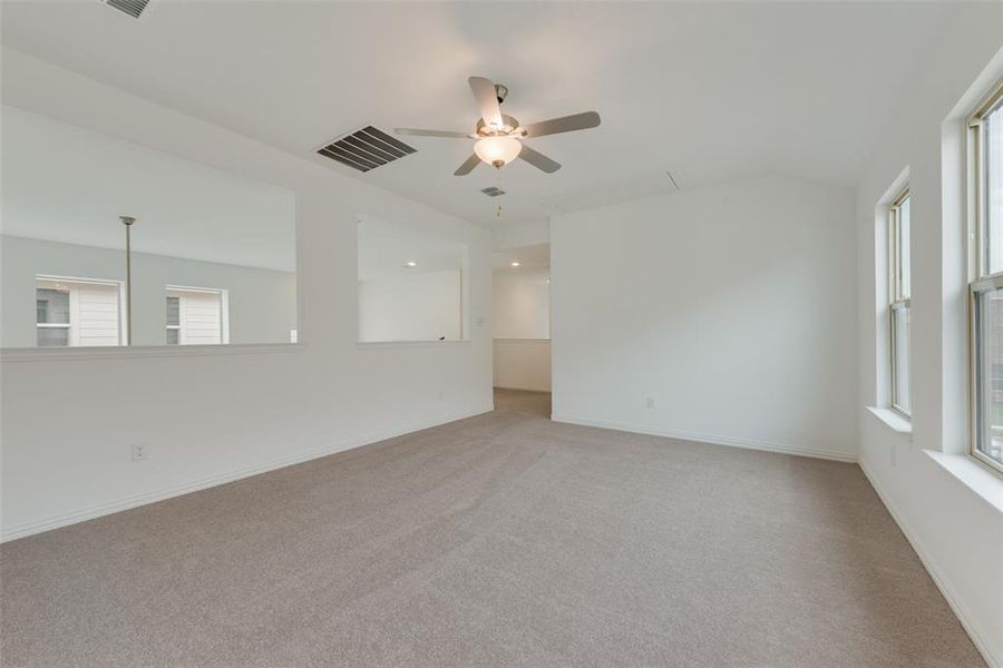 Empty room featuring ceiling fan, a healthy amount of sunlight, and light colored carpet