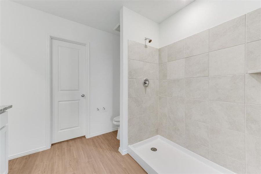 Bathroom featuring vanity, toilet, hardwood / wood-style flooring, and tiled shower