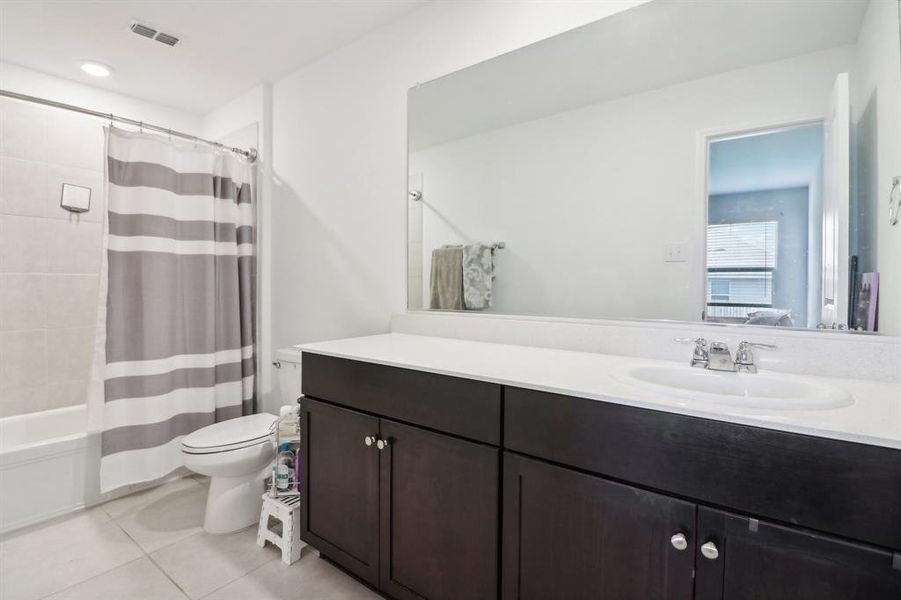 Full bathroom featuring shower / tub combo with curtain, tile patterned floors, vanity, and toilet