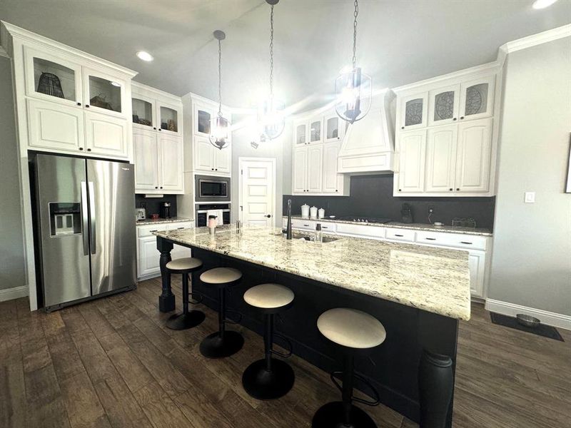 Kitchen with a center island with sink, premium range hood, white cabinetry, and stainless steel appliances