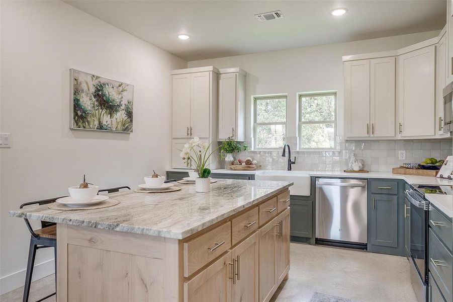 Kitchen with gray cabinetry, tasteful backsplash, sink, a kitchen island, and stainless steel appliances