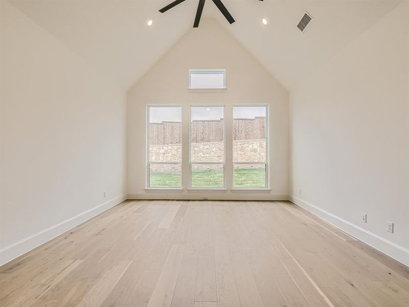 Empty room featuring high vaulted ceiling, ceiling fan, and light hardwood / wood-style flooring