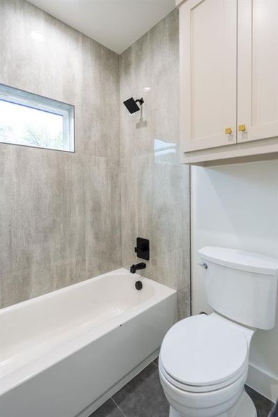 Bathroom featuring tile patterned flooring, tiled shower / bath, and toilet