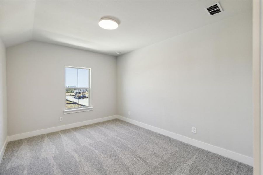 Spare room featuring light carpet and lofted ceiling