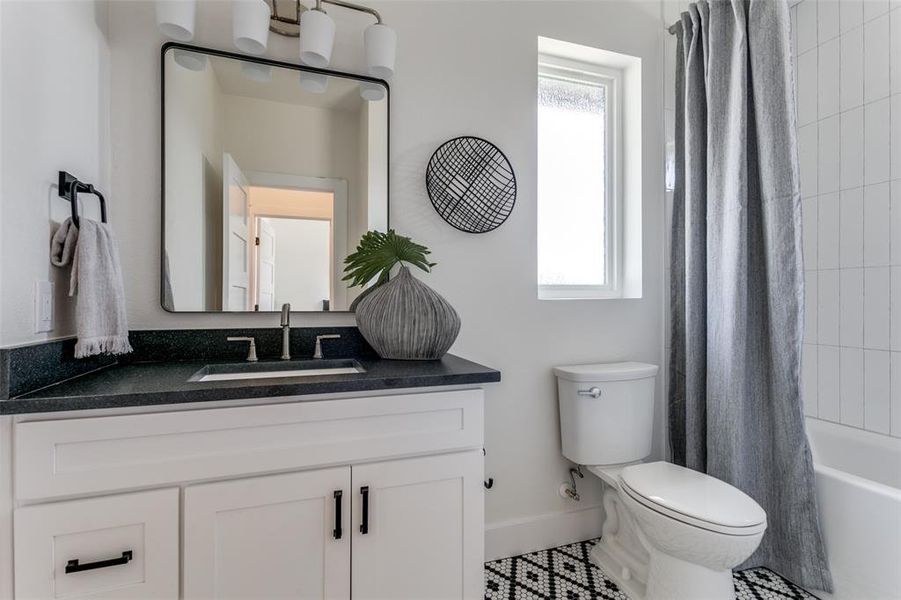 Full bathroom featuring a wealth of natural light, vanity, toilet, and shower / bathtub combination with curtain