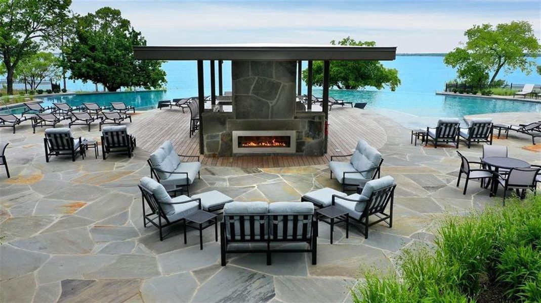 View of patio / terrace featuring an outdoor stone fireplace and a community pool